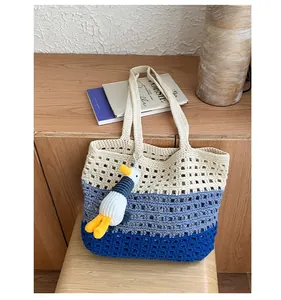 Close-up of handmade crochet tote bag with blue gradient stripes and cute duck charm
