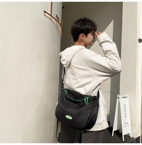 Detail of black nylon crossbody bag with neon green zippers and adjustable straps