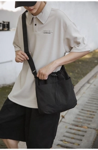 Close-up of black nylon drawstring bucket bag showing adjustable shoulder strap and texture