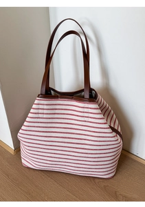 Detailed view of red and white striped canvas tote bag with premium brown leather handles