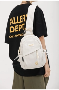 Detail view of cream nylon crossbody bag with side pocket and embroidered yellow logo