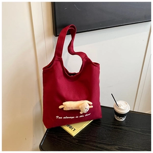Close-up of wine red canvas tote bag with plush cat appliqué and white embroidered text