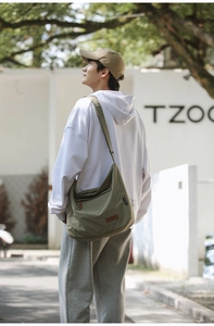 Outdoor lifestyle shot of an army green large capacity water-repellent messenger bag