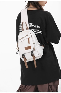Detailed back view of a woman wearing the canvas chest bag with brown strap details