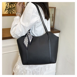 Close-up of black lychee grain tote bag with decorative geometric scarf and metal buckles