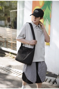 Detail of a large black nylon drawstring bucket bag with adjustable wide shoulder strap