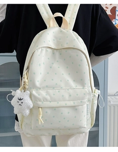 Detail of cream star pattern backpack with a plush star charm on a model's back
