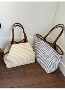 Detail of yellow and blue striped canvas tote bags with premium brown leather handles