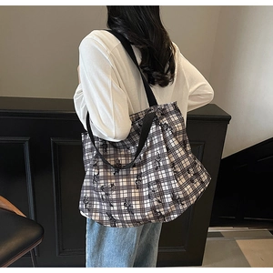 Detail of checkered canvas tote bag with black butterfly prints worn by a model