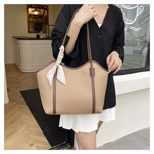 Close-up of khaki tote bag featuring lychee texture, brown trim and decorative scarf detail