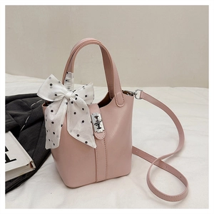 Dettaglio borsa a secchiello rosa opaco con foulard a pois e fibbia in metallo