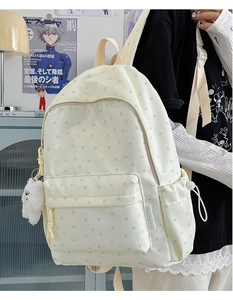 Close-up of white canvas backpack with green star print and cute sheep plush charm