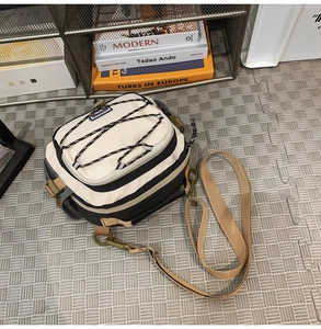 Detail of beige hiking crossbody bag with elastic bungee cords and nylon webbing