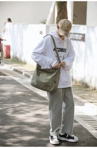 Outdoor shot of army green oversized canvas crossbody bag with adjustable wide strap