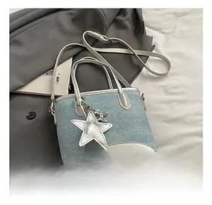 Détail du sac seau en jean bleu clair avec garniture argentée et breloque étoile sur blazer