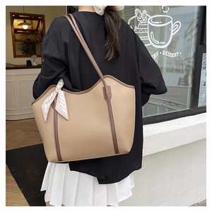 Detail of large tote bag with beige lychee texture and silk scarf decoration on strap