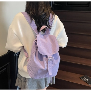 Détail d'un sac à dos en nylon violet lavande avec rabat et boucle porté par un mannequin