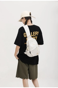 Detail view of the beige canvas chest bag with adjustable strap on a model's back