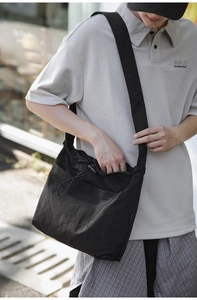 Macro detail of black nylon drawstring crossbody bag with front pocket and shoulder strap