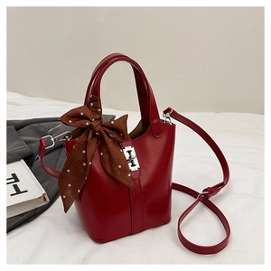 Dettaglio borsa a secchiello rossa con foulard a pois e chiusura a scatto argento