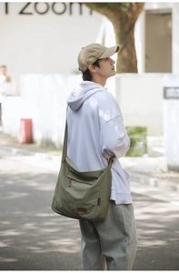 Outdoor shot of an olive green waterproof nylon messenger bag with adjustable strap
