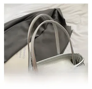 Détail du sac argenté scintillant avec doubles poignées robustes et fermeture éclair en métal