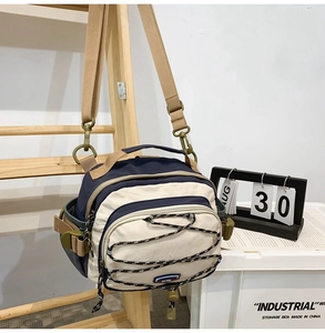 Detailed close-up of navy and beige crossbody bag with multi-pocket nylon construction