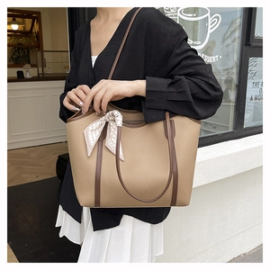 Detail of khaki tote bag with lychee texture and silk scarf accessory in coffee shop