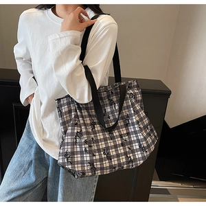 Detail shot of a large black and white checkered canvas tote bag worn on shoulder