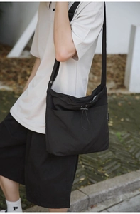 Close-up of lightweight black nylon drawstring crossbody bag with textured pleats
