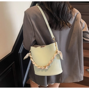 Sac seau vert menthe avec poignée chaîne et foulard léopard sur blazer gris foncé