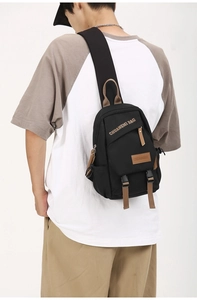 Close-up of black canvas chest bag featuring brown straps and brand logo detail