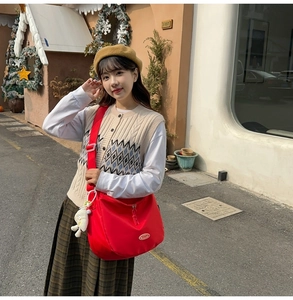 Close-up of red nylon crossbody bag with adjustable strap and cute sheep pendant
