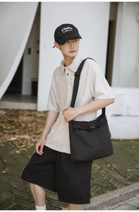 Detail of a large black nylon bucket bag with drawstring pocket on a casual model