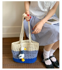 Detail of hand-woven knit tote bag with blue gradient pattern and small duck charm