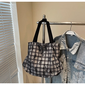 Detail of checkered canvas tote bag with black butterfly floral prints and sturdy handles