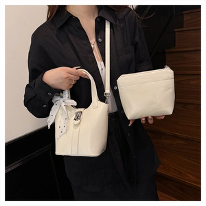 Dettaglio della borsa a secchiello crema con foulard a pois e pochette con cerniera