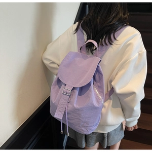 Modèle portant un sac à dos violet imperméable avec boucles en métal sur l'escalier