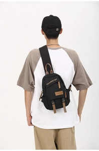 Detail showing back view of black canvas sling bag with brown straps on model