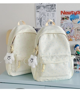 Detail of cream canvas backpacks with star prints and plush charms on a blue desk