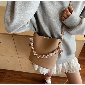 Détail du sac seau marron en cuir avec chaîne en foulard et bandoulière amovible