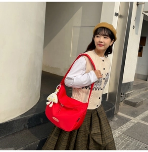 Detail of red nylon crossbody bag with white star plush charm in street style setting
