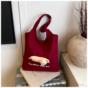 Close-up of deep wine red canvas tote bag featuring a cute yellow plush dog ornament