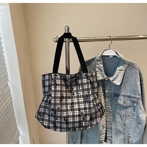 Detail of checkered canvas tote bag with cartoon print and black fabric shoulder strap