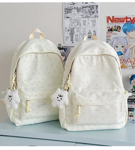 Detail of fabric backpack with star prints and a plush cloud charm on a study desk