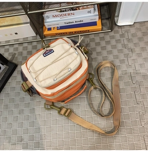 Top view of beige and orange nylon crossbody bag with mesh pockets and elastic cords