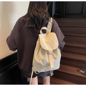 Détail du sac à dos en nylon beige avec fermeture à cordon et boucle en métal argenté