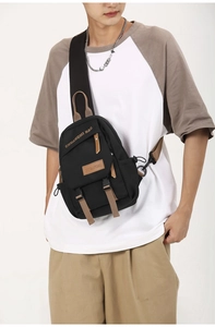 Detail of durable black sling bag with brown leather accents and branded buckle strap