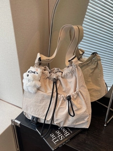 Large cream drawstring crossbody bucket bag with plush dog charm shown in mirror reflection