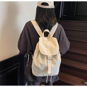 Détail du sac à dos en nylon crème avec fermeture à rabat et boucle métallique fine